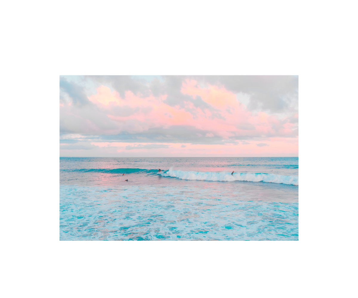 Sunset over a calm ocean with pink and orange clouds.
