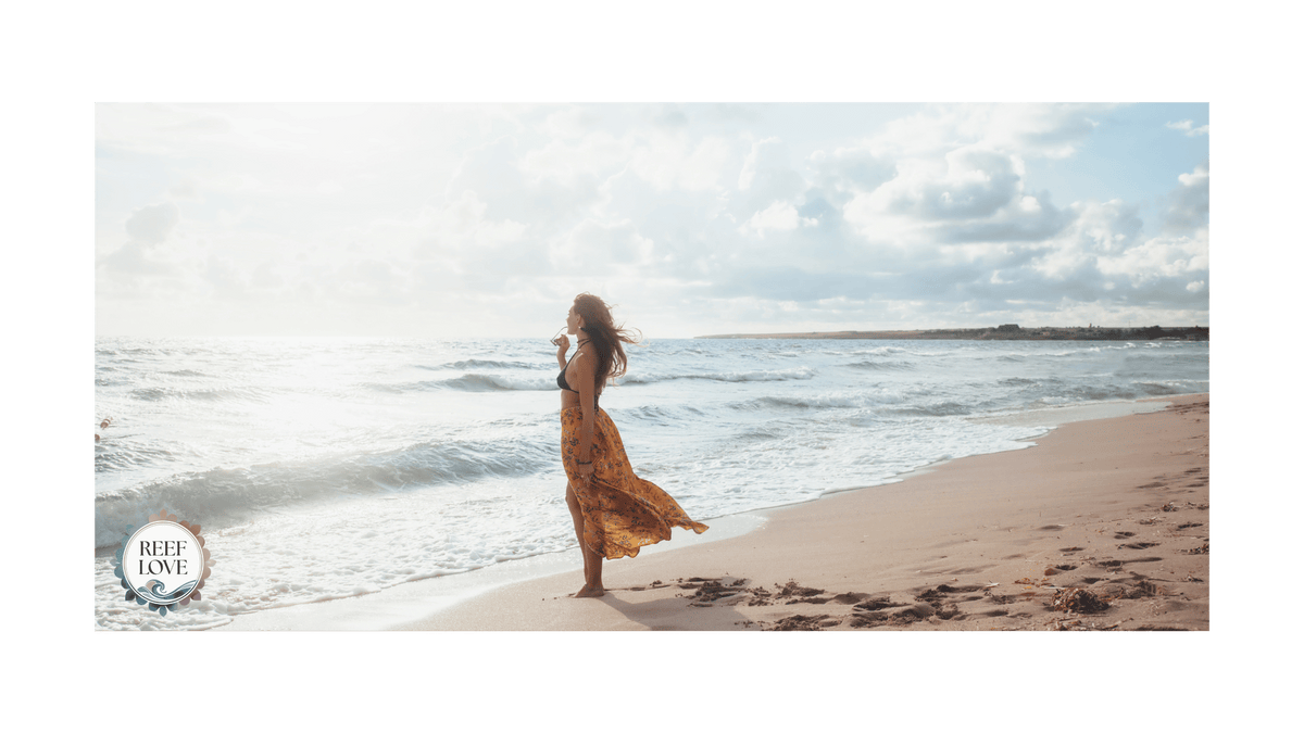 person standing on beach overlooking the ocean reef love logo in corner