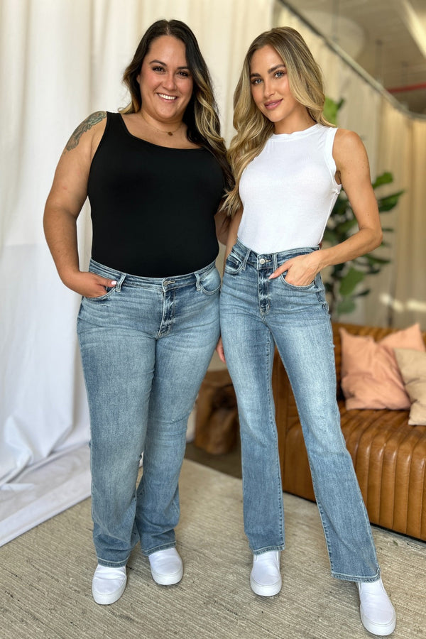 two women wearing tank tops and jeans standing indoors
