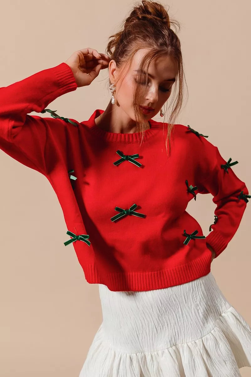 woman wearing a red long sleeve sweater with green ribbon bow accents