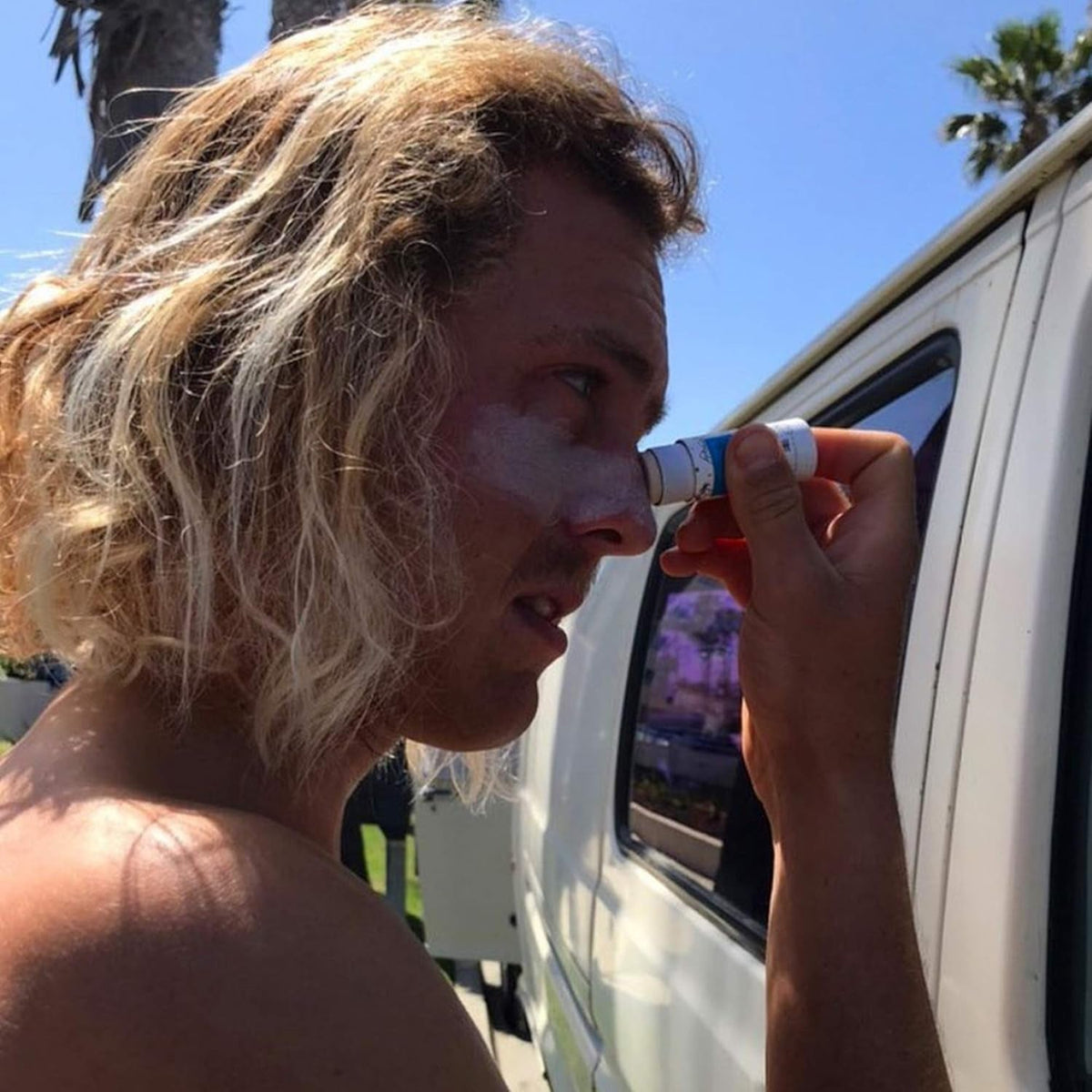 person putting on colored zinc sunscreen stick outdoors
