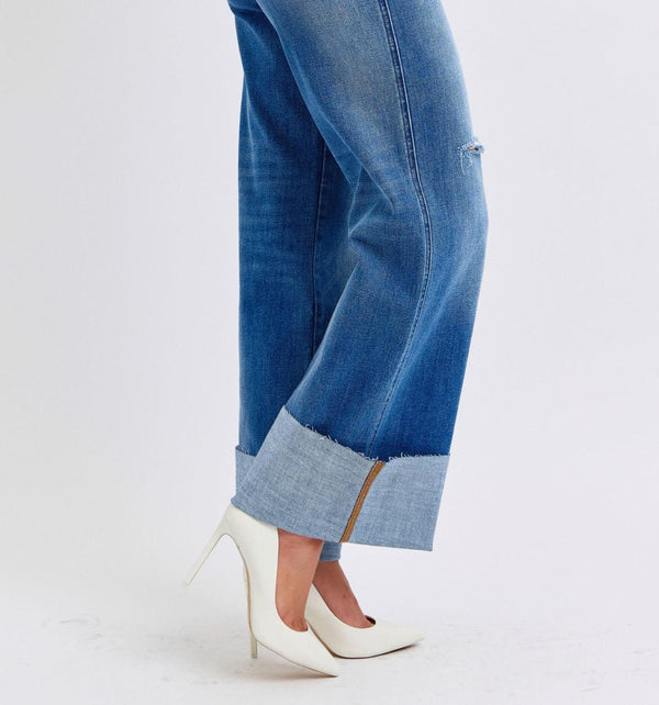 person wearing white heels and wide leg cuffed medium wash jeans