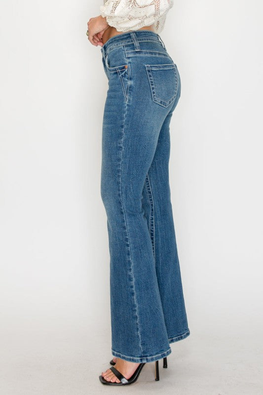 person wearing flare blue jeans and heels against white background