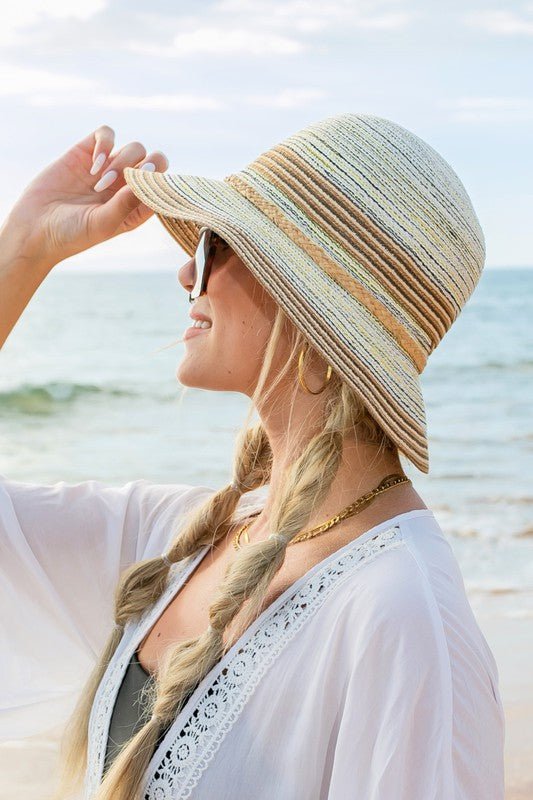 woman standing on beach wearing beige color sunhat.