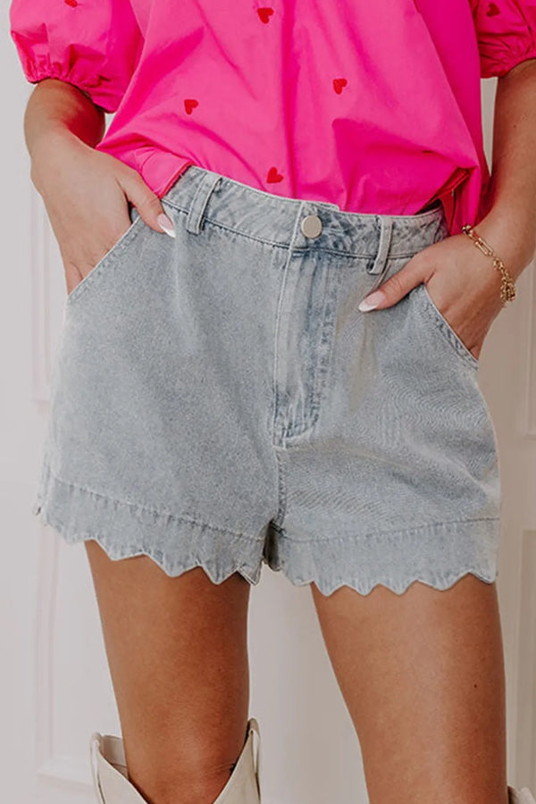 woman wearing pink top with scallop hem light wash denim jean shorts