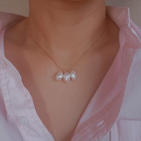woman in pink shirt wearing delicate three pearl gold chain necklace