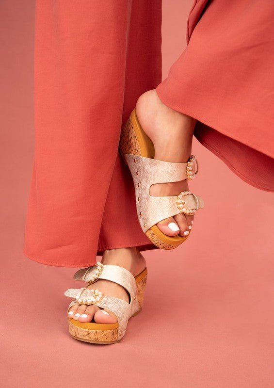 person wearing wide leg orange pants with platform wedge slide-on buckle sandals in gold