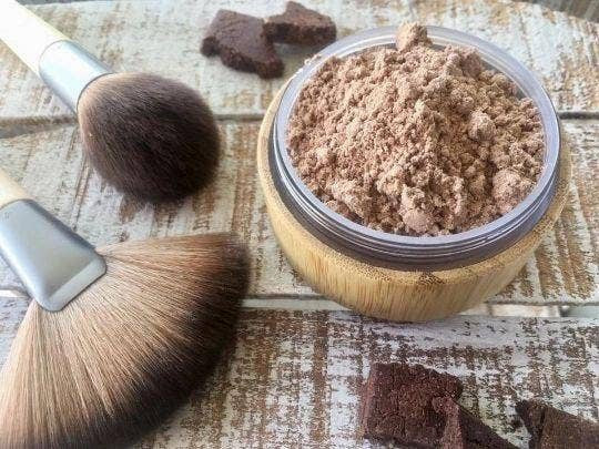 face bronzing powder with brushes laying on rustic wooden table