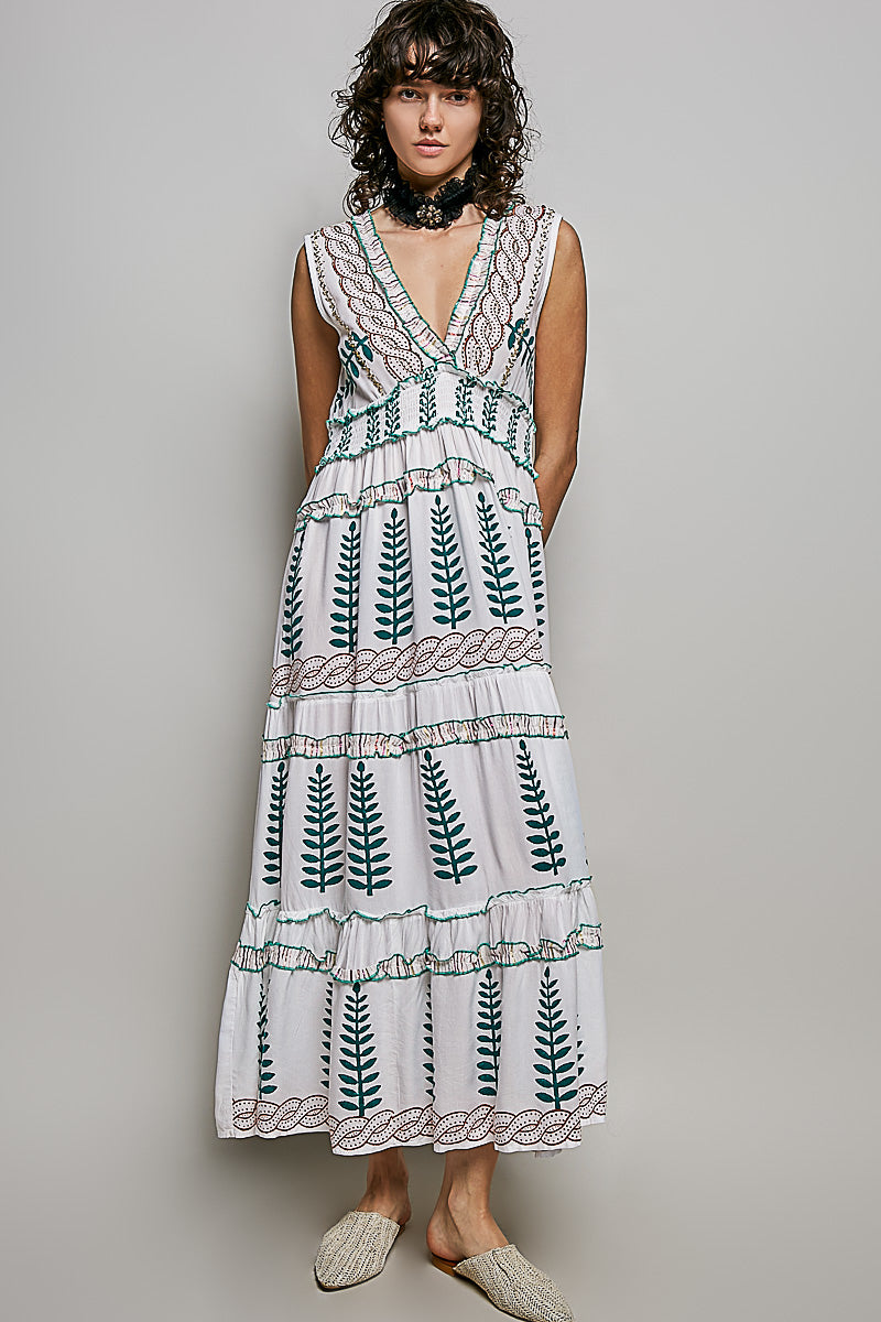 Ivory V-neck sleeveless tiered dress with green leafy floral print, smocked waistband, and ruffle accents.