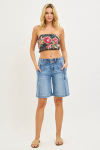 Woman wearing a floral bandeau top and denim shorts on a white background