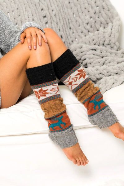 Leg warmers with a pattern worn by a person sitting on a textured surface.
