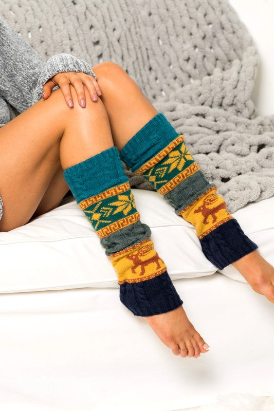 Leg warmers with a pattern worn by a person sitting on a textured surface.