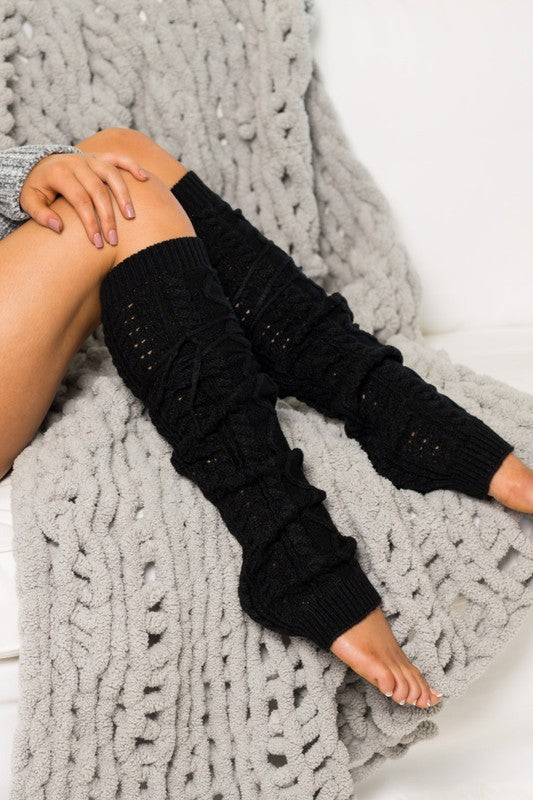 Person wearing black leg warmers on a gray textured blanket