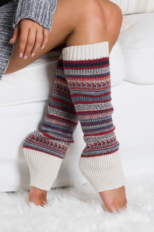 Leg warmers with a colorful pattern worn by a person sitting on a white couch.