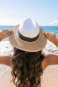 Person wearing a straw hat on a beach with ocean view