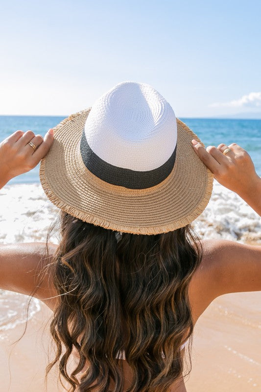 Person wearing a straw hat on a beach with ocean view