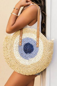 Woven handbag with circular blue design held by a person against a neutral background