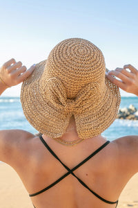 Person wearing a straw hat with a bow at the beach