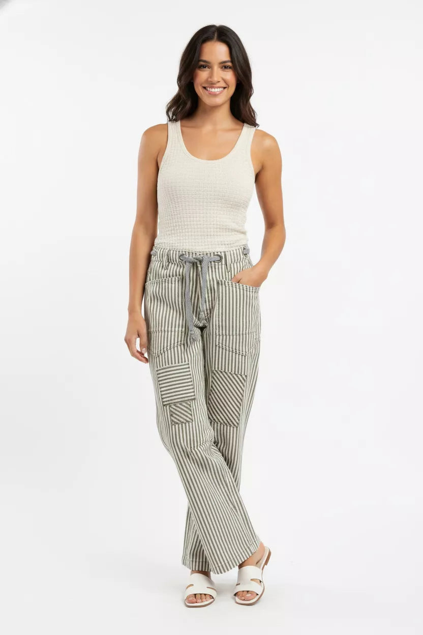 Woman wearing a sleeveless top and striped pants on a white background
