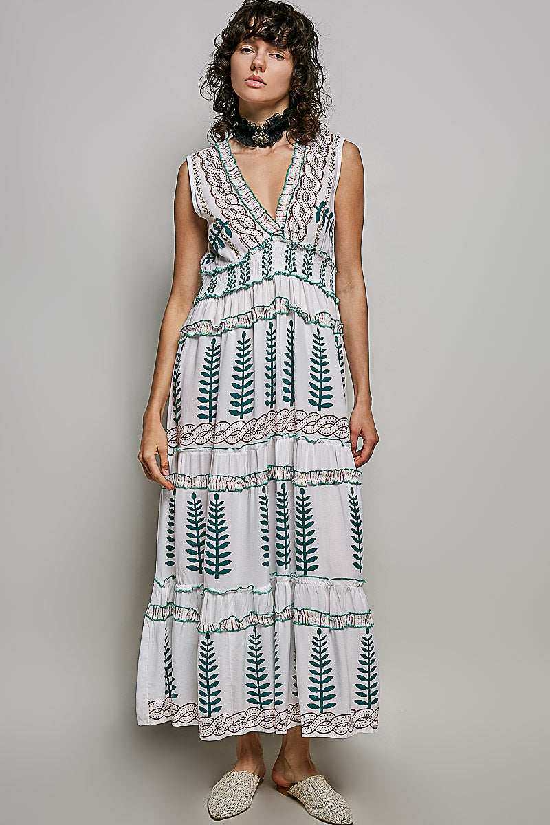 Ivory V-neck sleeveless tiered dress with green leafy floral print, smocked waistband, and ruffle accents.