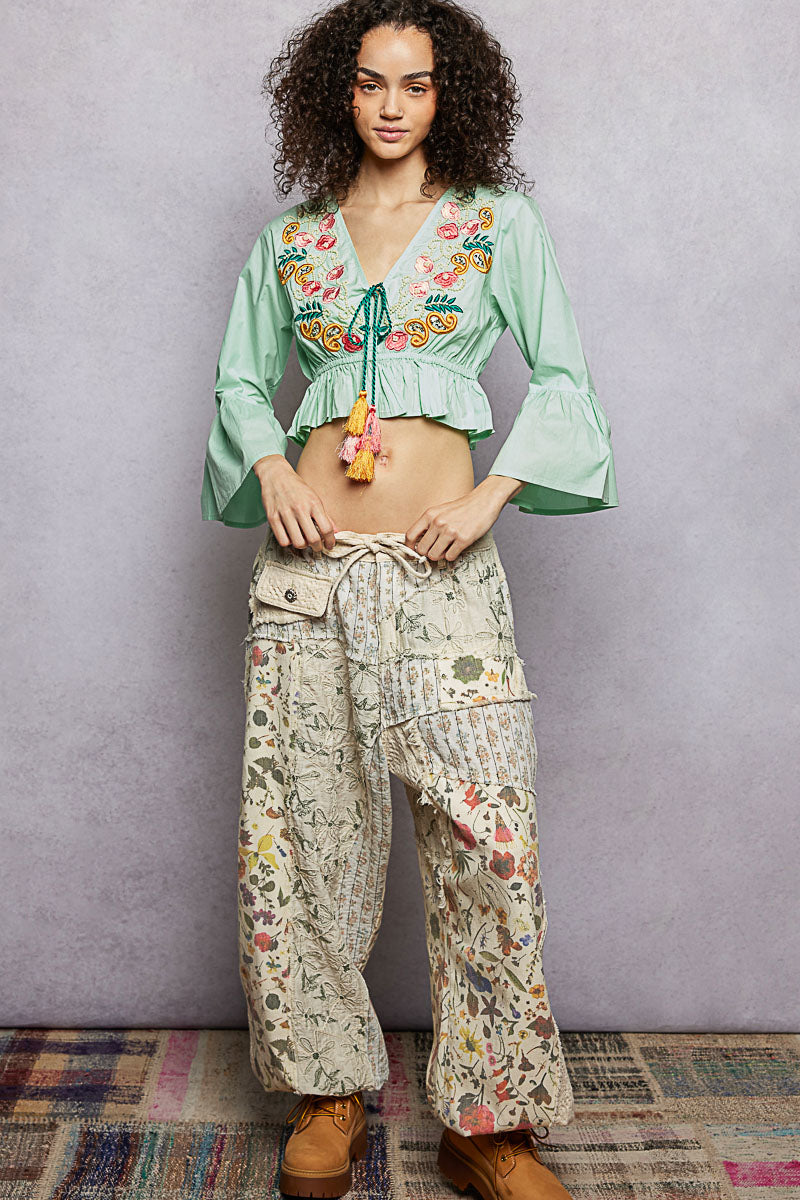 Mint Boho Floral Embroidered Cropped Blouse with braided tie, tassel, and flared ruffle sleeves.