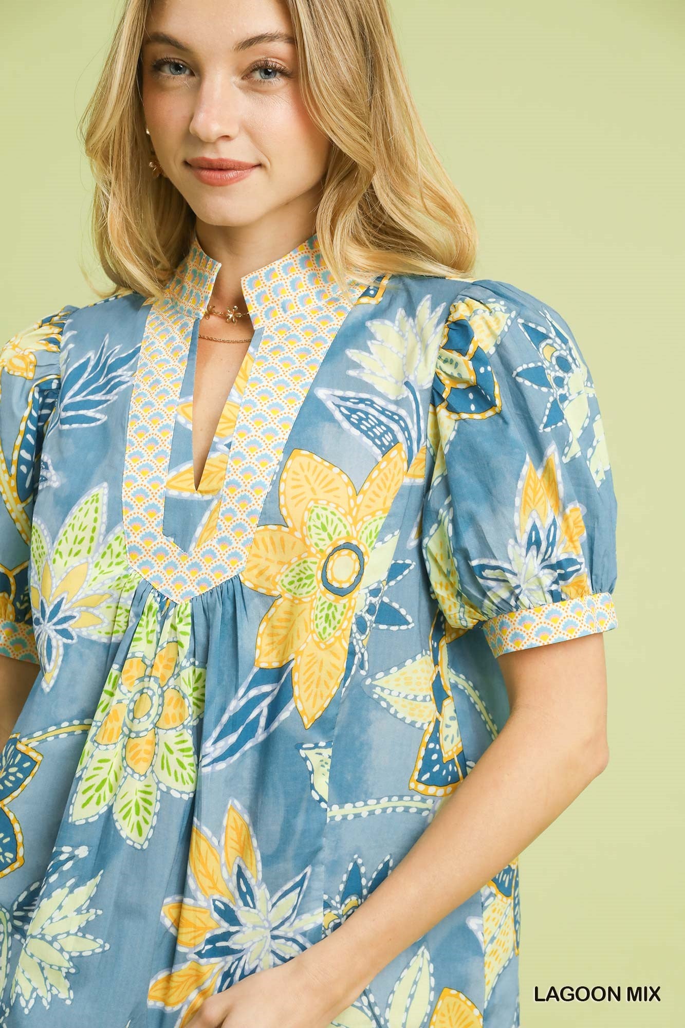Vibrant blue cotton blouse with yellow floral print, high neckline, and chic puff sleeves.