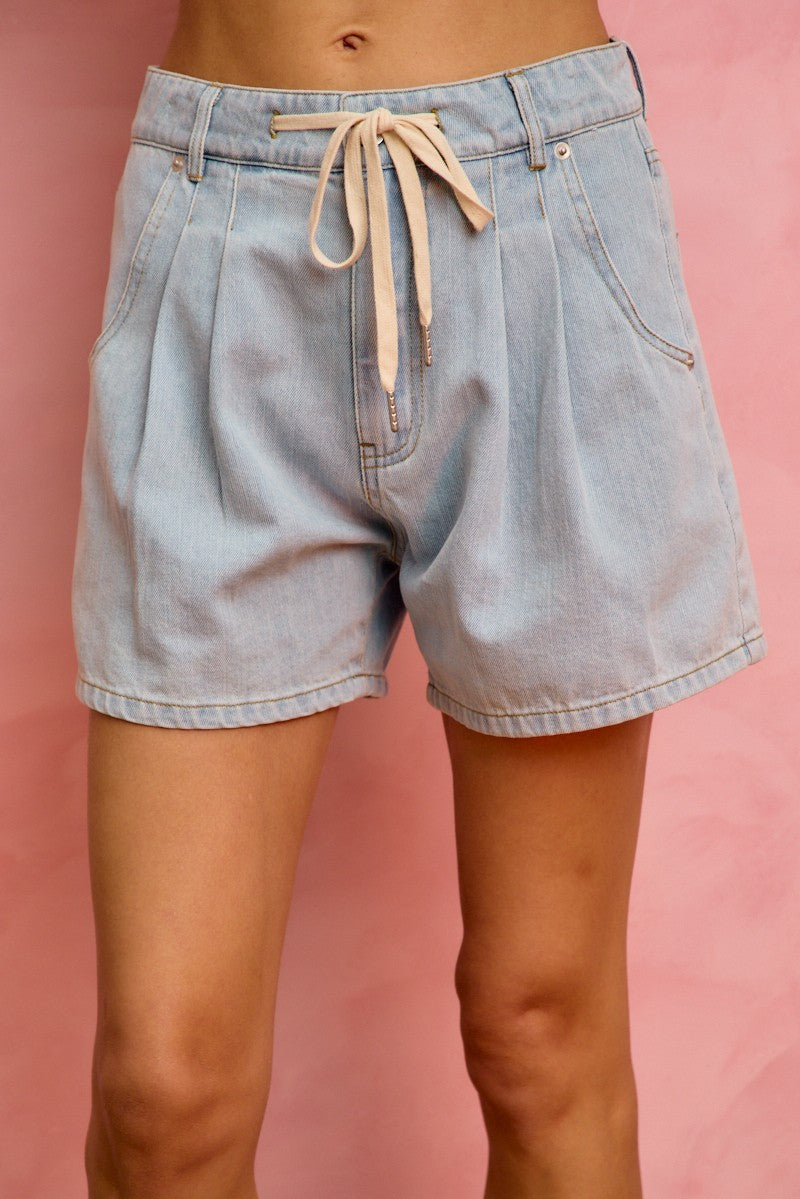 Light blue denim shorts with a drawstring on a pink background