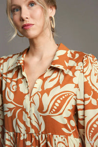 Woman wearing Floral Tiered Midi Shirt Dress-Flowy floral tiered midi shirt dress with 3/4 sleeves in rust + beige print. Boho-chic style in standard & plus sizes for casual or dressy days.
