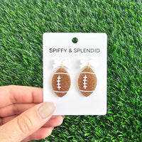 Bow Football Earrings-Football Season Must-have Earrings. Cheer in style with our Game Day Bow Football Earrings! Featuring a dainty white bow paired with a glittery brown football.