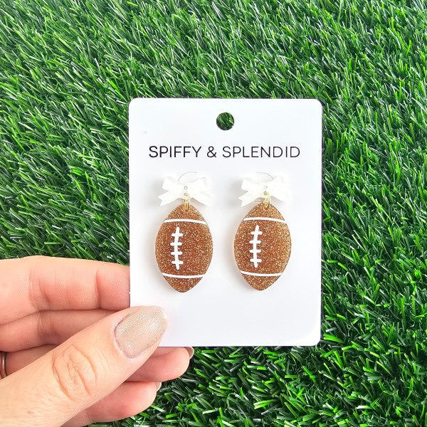 Bow Football Earrings-Football Season Must-have Earrings. Cheer in style with our Game Day Bow Football Earrings! Featuring a dainty white bow paired with a glittery brown football.