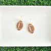 Bow Football Earrings-Football Season Must-have Earrings. Cheer in style with our Game Day Bow Football Earrings! Featuring a dainty white bow paired with a glittery brown football.