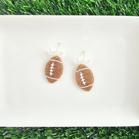 Bow Football Earrings-Football Season Must-have Earrings. Cheer in style with our Game Day Bow Football Earrings! Featuring a dainty white bow paired with a glittery brown football.