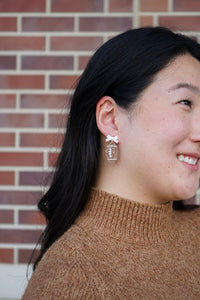 Bow Football Earrings-Football Season Must-have Earrings. Cheer in style with our Game Day Bow Football Earrings! Featuring a dainty white bow paired with a glittery brown football.