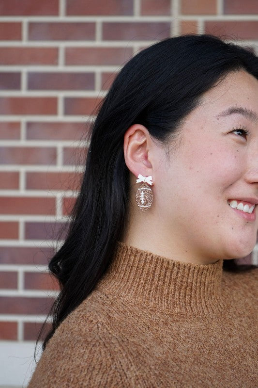 Bow Football Earrings-Football Season Must-have Earrings. Cheer in style with our Game Day Bow Football Earrings! Featuring a dainty white bow paired with a glittery brown football.