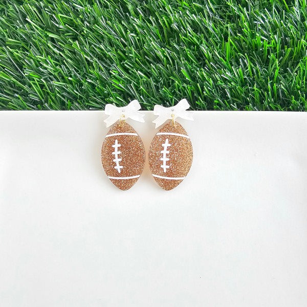 Bow Football Earrings-Football Season Must-have Earrings. Cheer in style with our Game Day Bow Football Earrings! Featuring a dainty white bow paired with a glittery brown football.