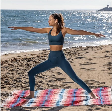Woman practicing yoga on a beach with ocean in the background