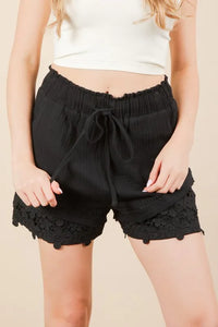 Women's black Lace contrast woven shorts are chic and stylish bottoms that feature delicate lace accents. These shorts combine a woven fabric with lace detailing.