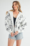 Shop Oita Floral Zip Front Hoodie-Cozy meets cool in the Oita Floral Zip-Up Hoodie - sherpa-lined warmth, bold floral print, and a bomber fit make this your new cold-weather go-to.-available at Reef Love online boho-chic boutique