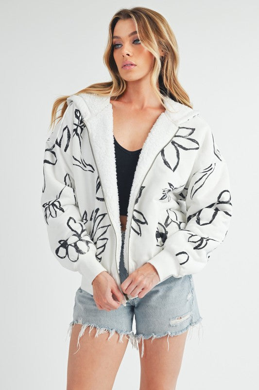 Shop Oita Floral Zip Front Hoodie-Cozy meets cool in the Oita Floral Zip-Up Hoodie - sherpa-lined warmth, bold floral print, and a bomber fit make this your new cold-weather go-to.-available at Reef Love online boho-chic boutique