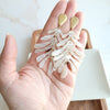 Shop Palm Earrings - Seashell Cream-Seashell cream palm leaf earrings with gold accents. Lightweight, tropical-inspired statement style—perfect for vacations, summer events, or everyday chic.-available at Reef Love online boho-chic boutique