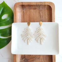 Shop Palm Earrings - Seashell Cream-Seashell cream palm leaf earrings with gold accents. Lightweight, tropical-inspired statement style—perfect for vacations, summer events, or everyday chic.-available at Reef Love online boho-chic boutique