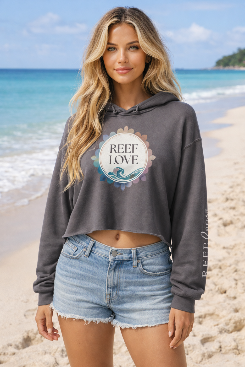 Woman wearing a hoodie with 'Reef Love' logo on a beach