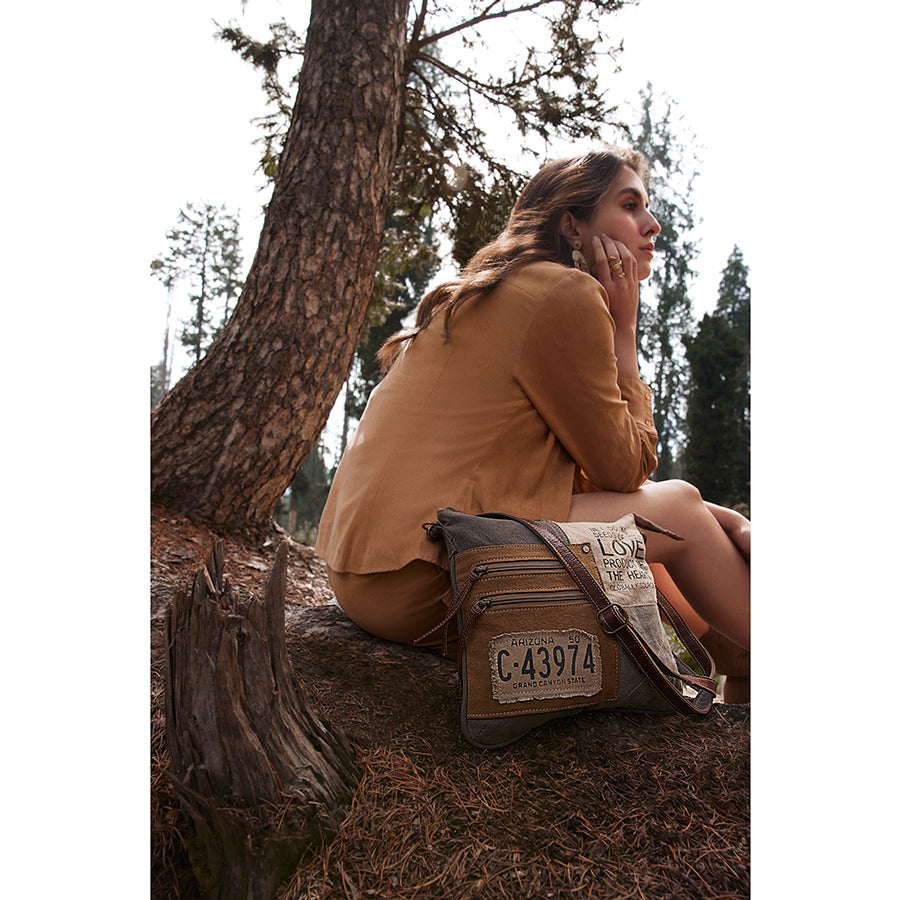 Woman sitting in a forest with a leather bag on her lap