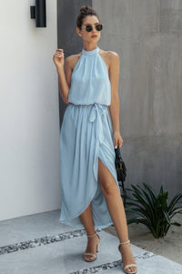 Woman wearing Halter Neck Empire Waist Spilt Dress-Turn heads with this Halter Empire Waist Split Dress. Designed with a flattering halter neckline, elegant empire waist, and a stylish front split for added drama.