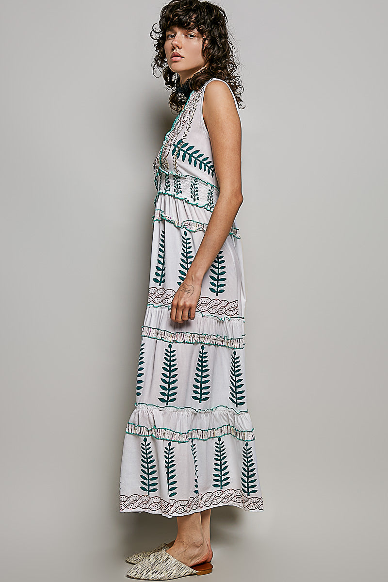 Ivory V-neck sleeveless tiered dress with leafy floral print, smocked waistband, and ruffle accents.