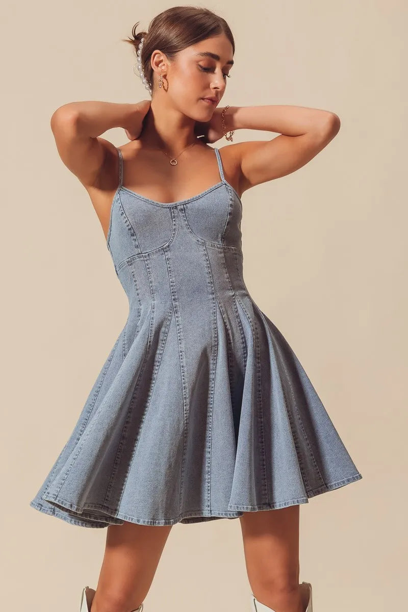 Woman wearing Fit and Flare Denim Mini Dress-Fit & Flare Denim Mini Dress A denim classic—where feminine meets effortless. Featuring a fitted bodice, pleated A-line skirt, and adjustable spaghetti straps.