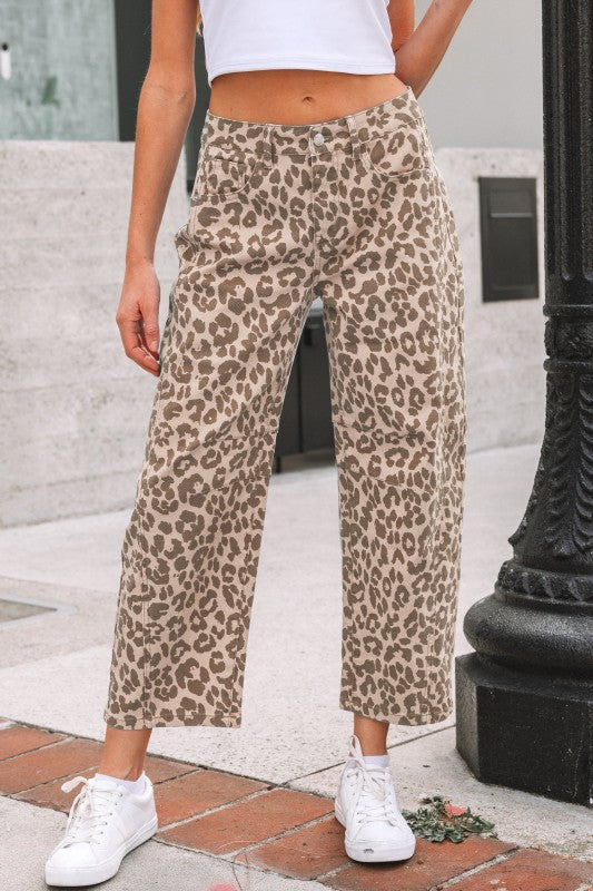 Person wearing leopard print pants and white sneakers on a city street.